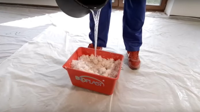 Wasser in einen Behälter mit flüssiger Tapete gießen