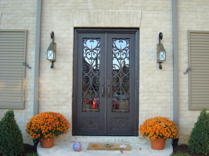 Veranda eines Landhauses mit einer Eingangstür mit Schmiedeeisen und Glas
