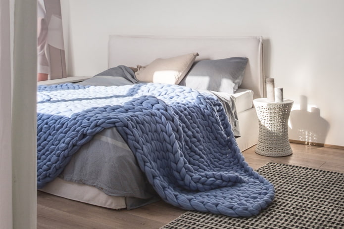 кревет са прекривачем са крупним плетивом у спаваћој соби