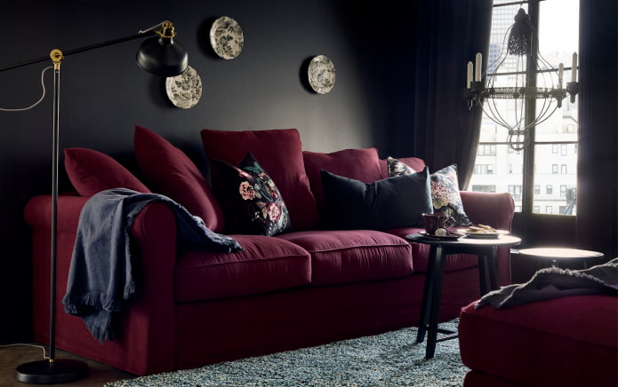 burgundy sofa sa isang itim na dingding