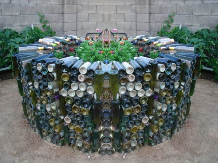ein hohes Blumenbeet aus bunten Glasflaschen, die im Kreis angeordnet sind